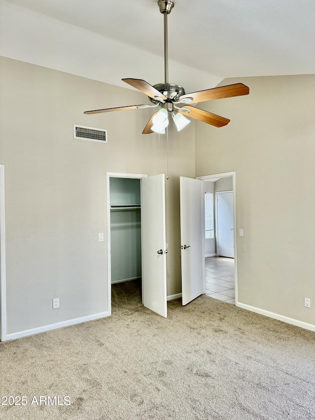 unfurnished bedroom featuring a closet, a walk in closet, carpet, ceiling fan, and high vaulted ceiling