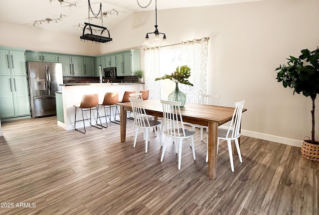 dining area featuring vaulted ceiling and wood-type flooring