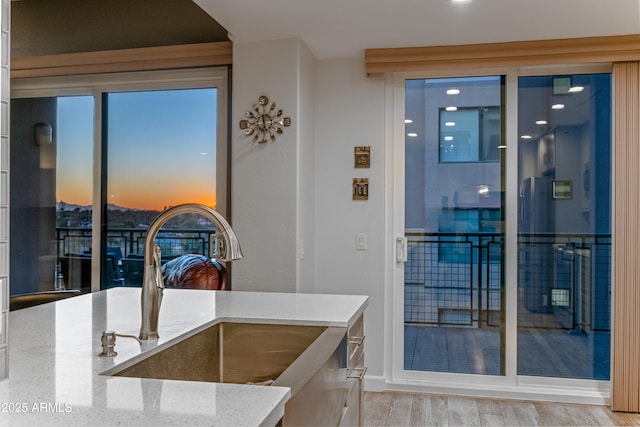 kitchen with light stone countertops, sink, and light hardwood / wood-style flooring