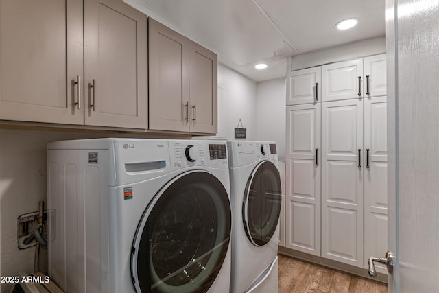 laundry area with washer and clothes dryer, cabinets, and light wood-type flooring