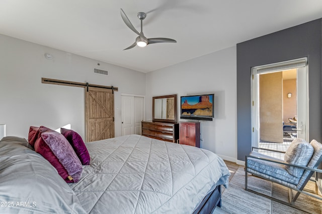 bedroom featuring a barn door, ceiling fan, and a closet