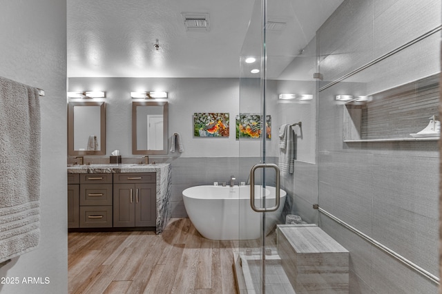 bathroom with hardwood / wood-style flooring, vanity, separate shower and tub, and tile walls