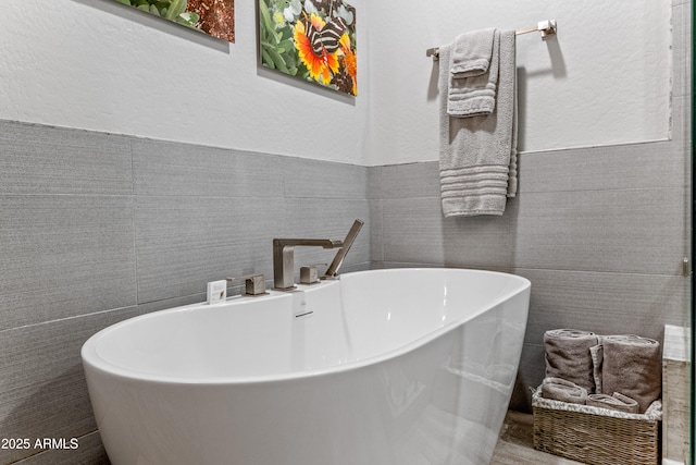 bathroom with a tub to relax in and tile walls