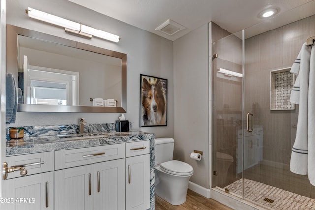 bathroom featuring a shower with door, vanity, hardwood / wood-style floors, and toilet