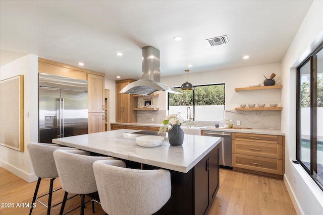 7553 E Woodshire Cv, Scottsdale, AZ 85258 - kitchen with visible vents, a center island, island exhaust hood, stainless steel appliances, and open shelves