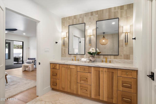 ensuite bathroom featuring marble finish floor, double vanity, a sink, and connected bathroom