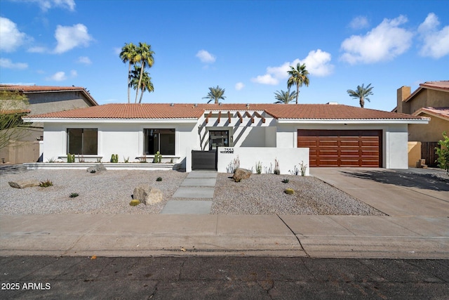 view of front facade featuring concrete driveway, a tiled roof, an attached garage, and stucco siding