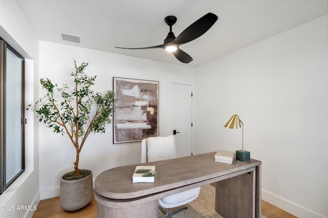 home office with baseboards, light wood-type flooring, visible vents, and a ceiling fan