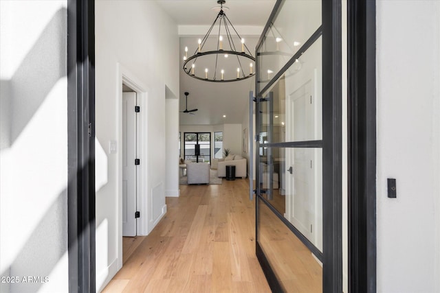 corridor with a chandelier and light wood-style flooring