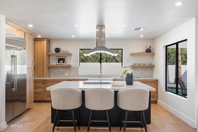 kitchen featuring open shelves, built in refrigerator, visible vents, and island range hood