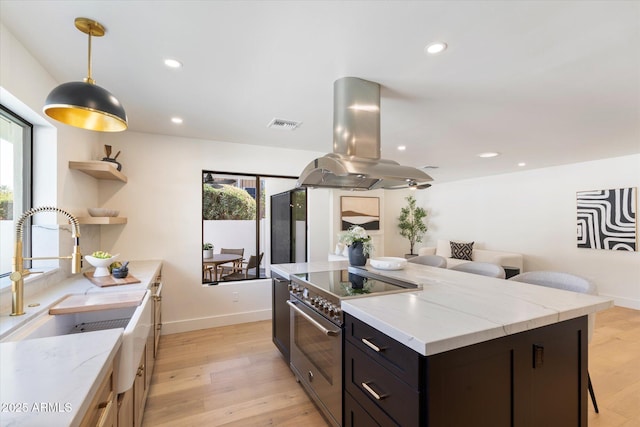 kitchen with stainless steel stove, a healthy amount of sunlight, island exhaust hood, and a sink