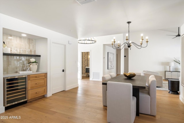 dining room featuring a bar, light wood-style floors, beverage cooler, and visible vents