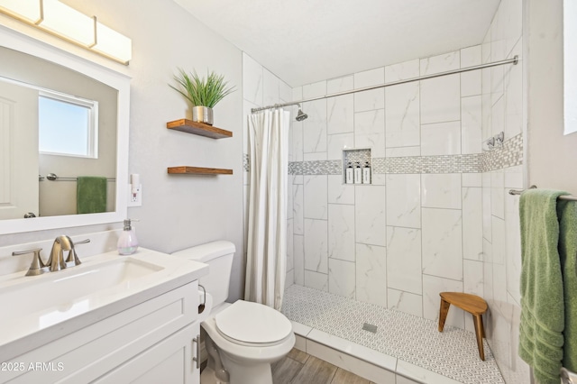 full bath with toilet, a tile shower, and vanity