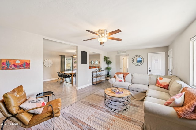 living room featuring baseboards, a ceiling fan, wood finished floors, and visible vents