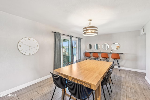 dining area with light wood-style floors, baseboards, a chandelier, and visible vents