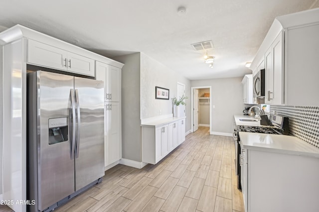 kitchen with light countertops, baseboards, appliances with stainless steel finishes, and decorative backsplash