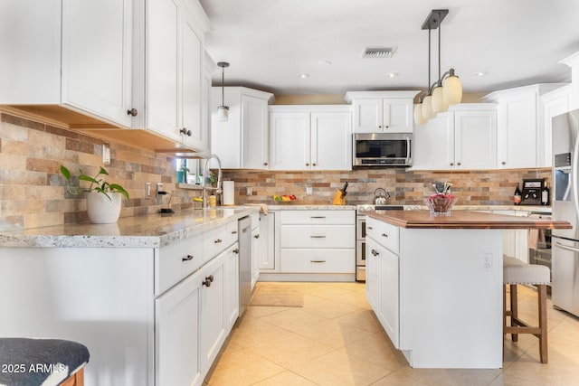12212 N 66th St, Scottsdale, AZ 85254 - kitchen featuring stainless steel appliances, a kitchen island, white cabinetry, and butcher block counters
