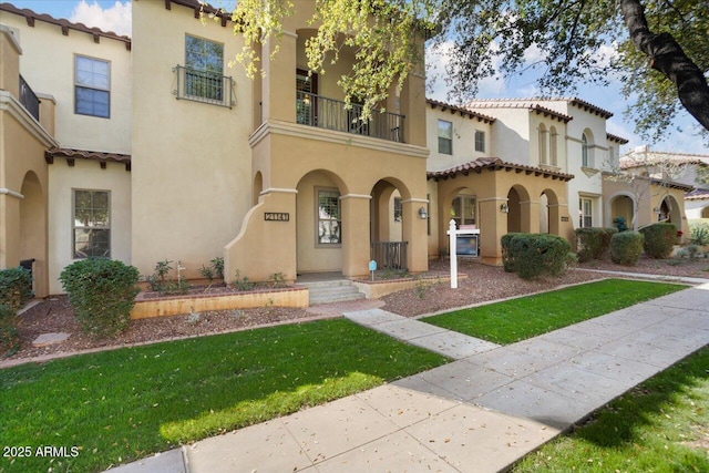 mediterranean / spanish home with a balcony and a front yard