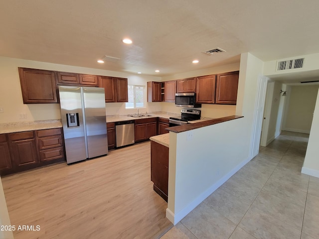 kitchen with stainless steel appliances, a peninsula, visible vents, and recessed lighting
