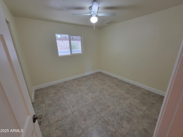 spare room featuring baseboards, a ceiling fan, visible vents, and light tile patterned floors