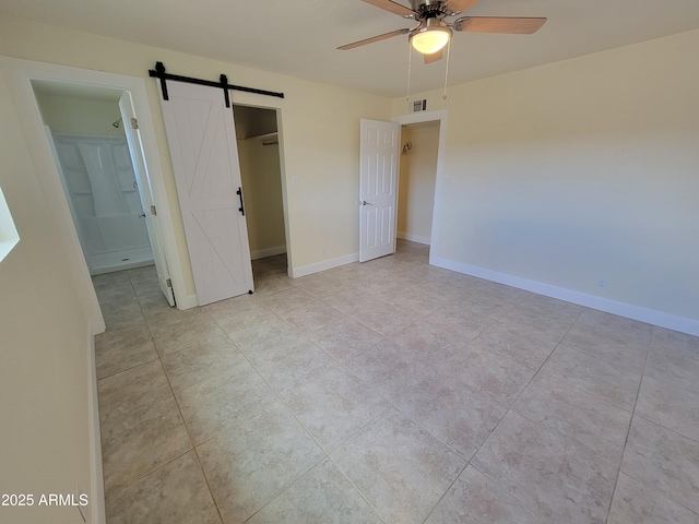 unfurnished bedroom with a barn door, ensuite bathroom, visible vents, and light tile patterned floors