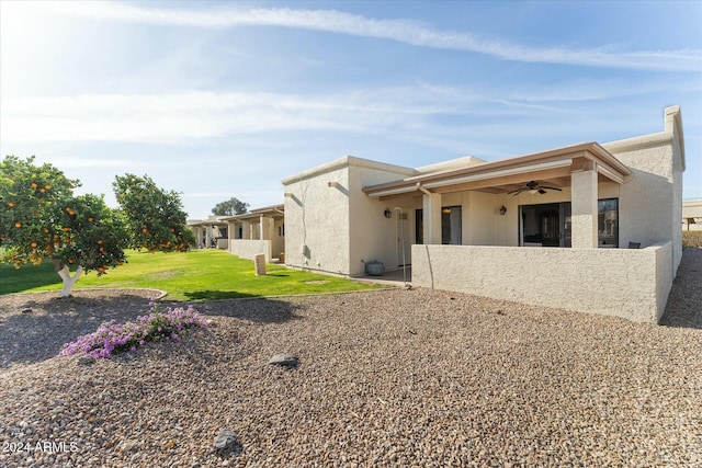 rear view of house with ceiling fan and a lawn