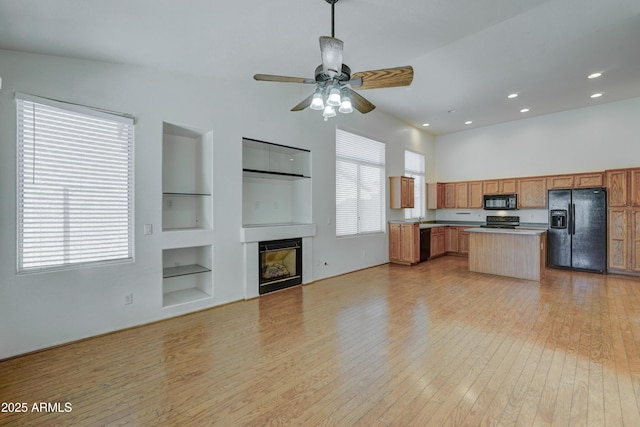 kitchen featuring plenty of natural light, a kitchen island, black appliances, and built in features