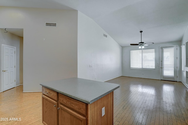 kitchen featuring ceiling fan, light hardwood / wood-style flooring, a center island, and vaulted ceiling