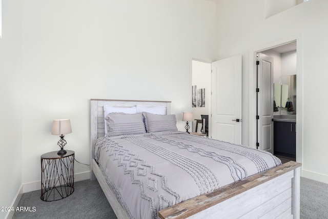 bedroom with a towering ceiling, ensuite bath, and dark carpet