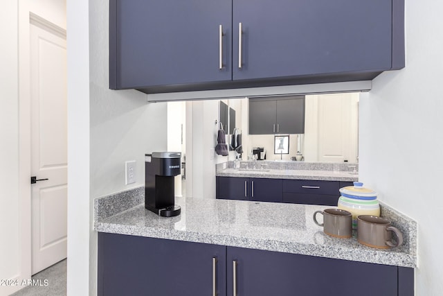 kitchen featuring light stone counters and blue cabinetry