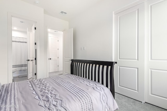 carpeted bedroom with a closet and ensuite bath