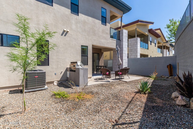 rear view of house featuring a balcony, central AC unit, and a patio area