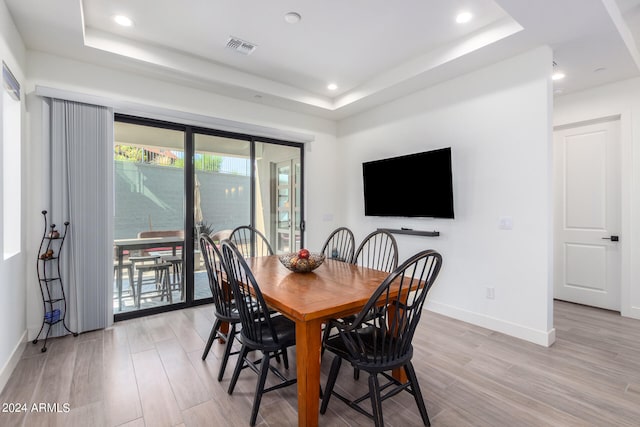 dining space with a tray ceiling and light hardwood / wood-style floors