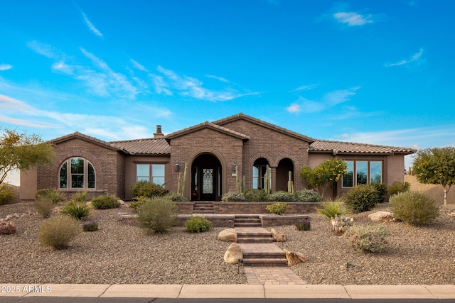 mediterranean / spanish home with brick siding and a tile roof