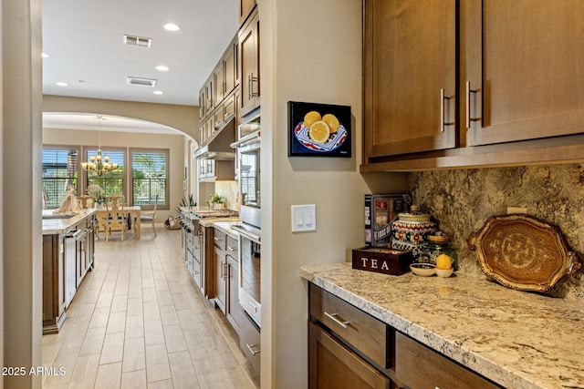 kitchen with a notable chandelier, gas stove, recessed lighting, light wood finished floors, and decorative backsplash