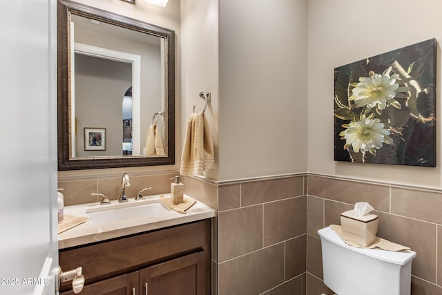 bathroom with vanity, tile walls, toilet, and wainscoting