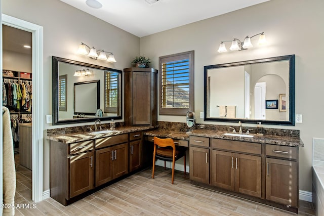 full bathroom with a sink, two vanities, and wood tiled floor