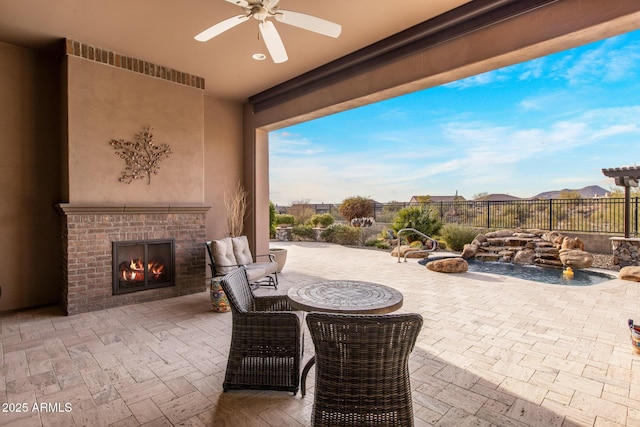 view of patio / terrace featuring fence, a ceiling fan, and an outdoor brick fireplace