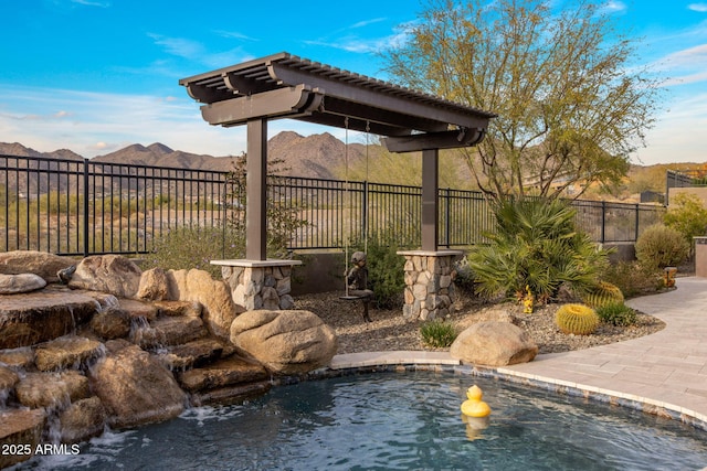 view of swimming pool with a mountain view and fence