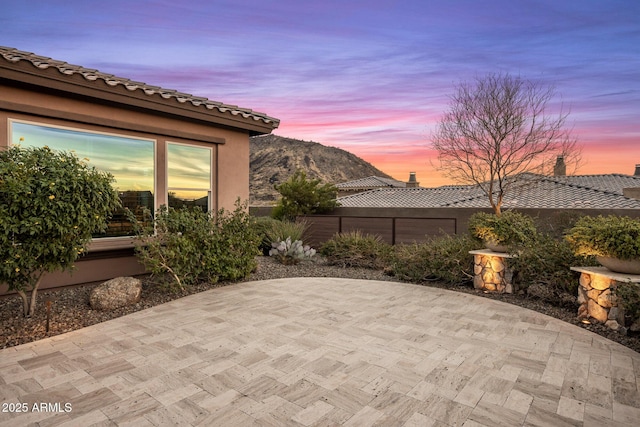 patio terrace at dusk featuring a mountain view and fence