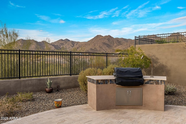 view of patio / terrace with a mountain view, area for grilling, a grill, and fence