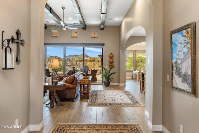 entrance foyer featuring baseboards, arched walkways, light wood-style floors, and a ceiling fan