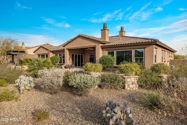 back of property featuring stucco siding, a tiled roof, a chimney, and a patio