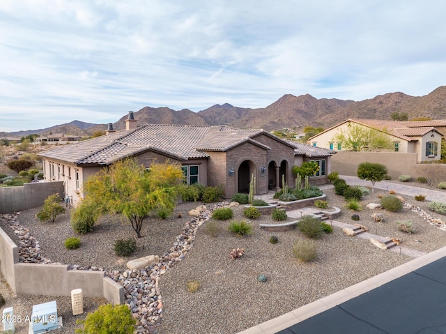 view of front of house featuring a mountain view, fence, stucco siding, and a tile roof