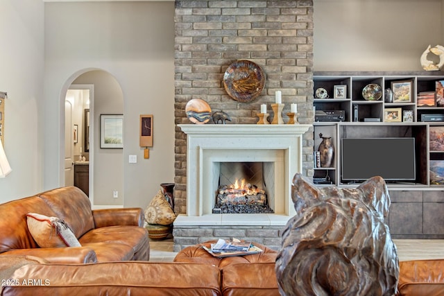 living room featuring arched walkways and a fireplace