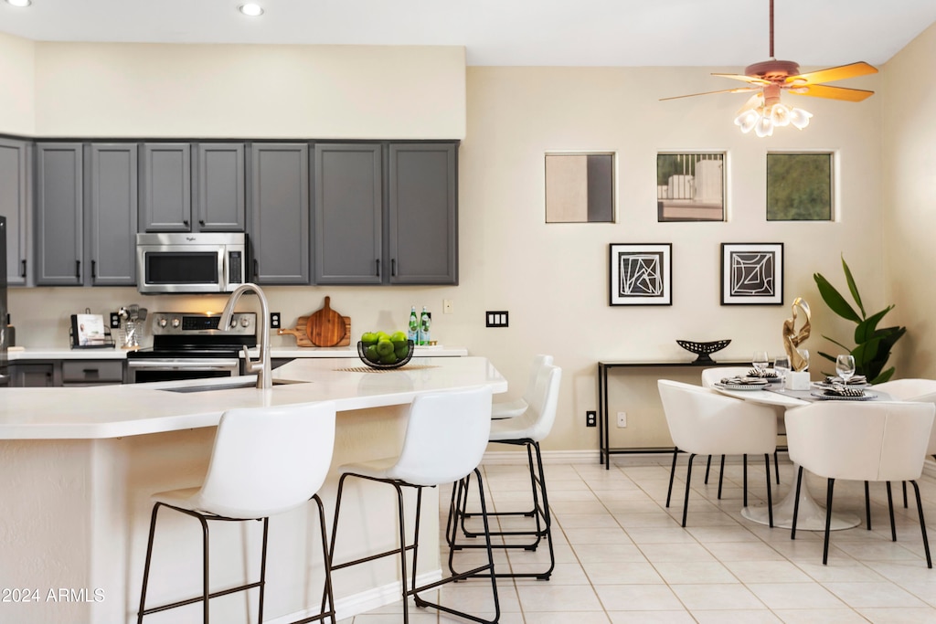 kitchen featuring sink, gray cabinetry, ceiling fan, light tile patterned flooring, and appliances with stainless steel finishes