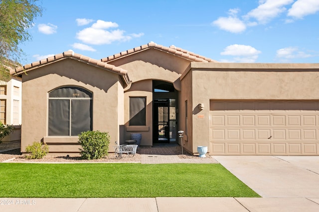 mediterranean / spanish-style house with a garage and a front lawn