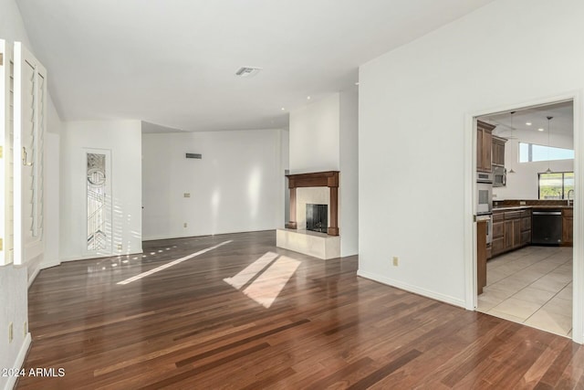 unfurnished living room featuring vaulted ceiling and light hardwood / wood-style flooring