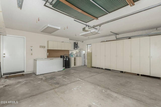 garage with electric water heater, electric panel, and a garage door opener