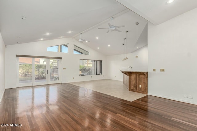 unfurnished living room featuring a wealth of natural light, light hardwood / wood-style flooring, high vaulted ceiling, and ceiling fan